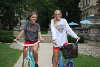 Smiling students sitting on bikes in front of Guerin Hall